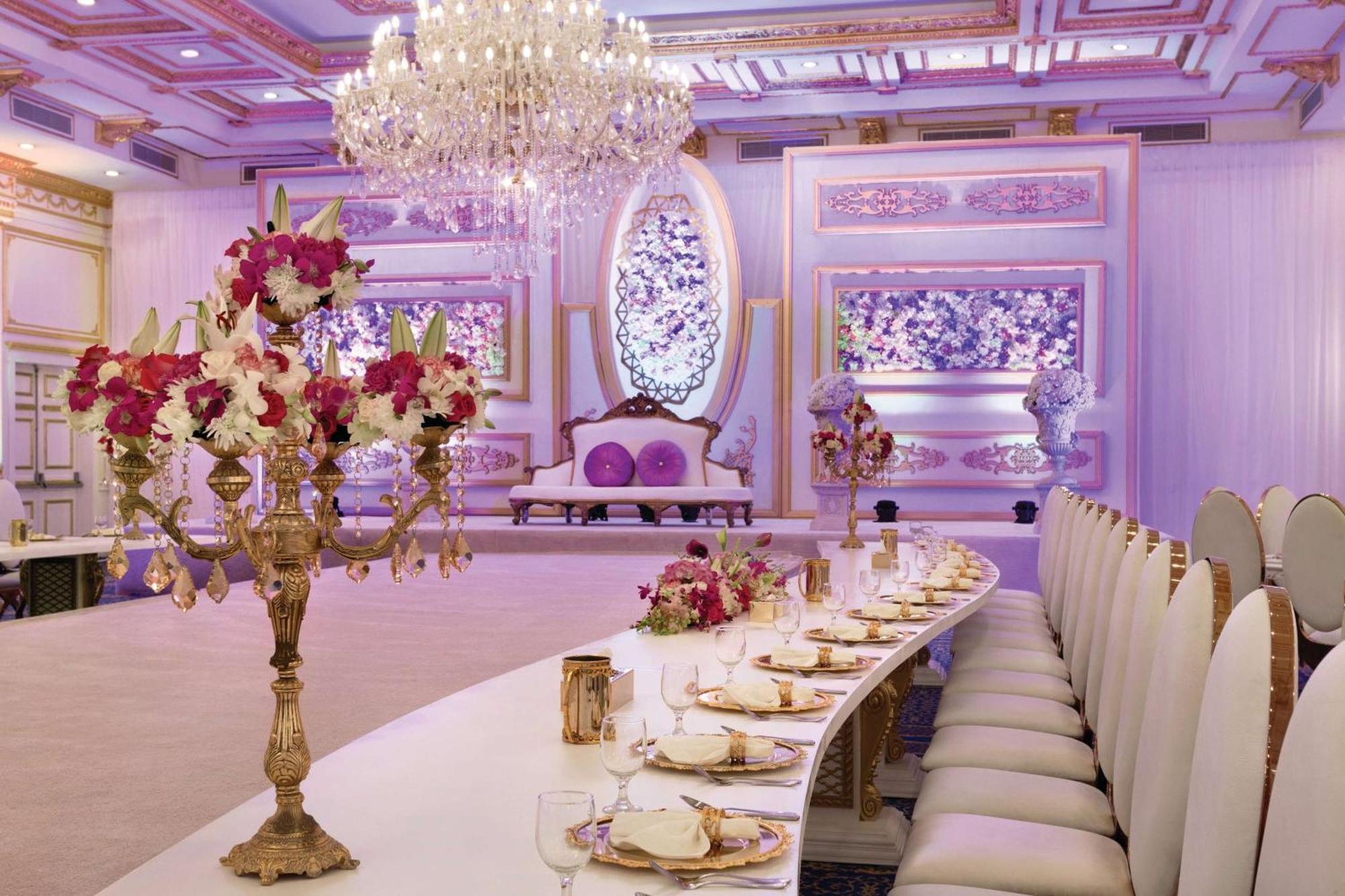 Grand Regency Doha, Trademark Collection By Wyndham Екстериор снимка The photo displays an elegantly decorated banquet or dining hall. It features a long, curved table set for a formal event, with fine china and floral centerpieces. Luxurious decorations include a grand chandelier hanging from the ceiling, and the wal
