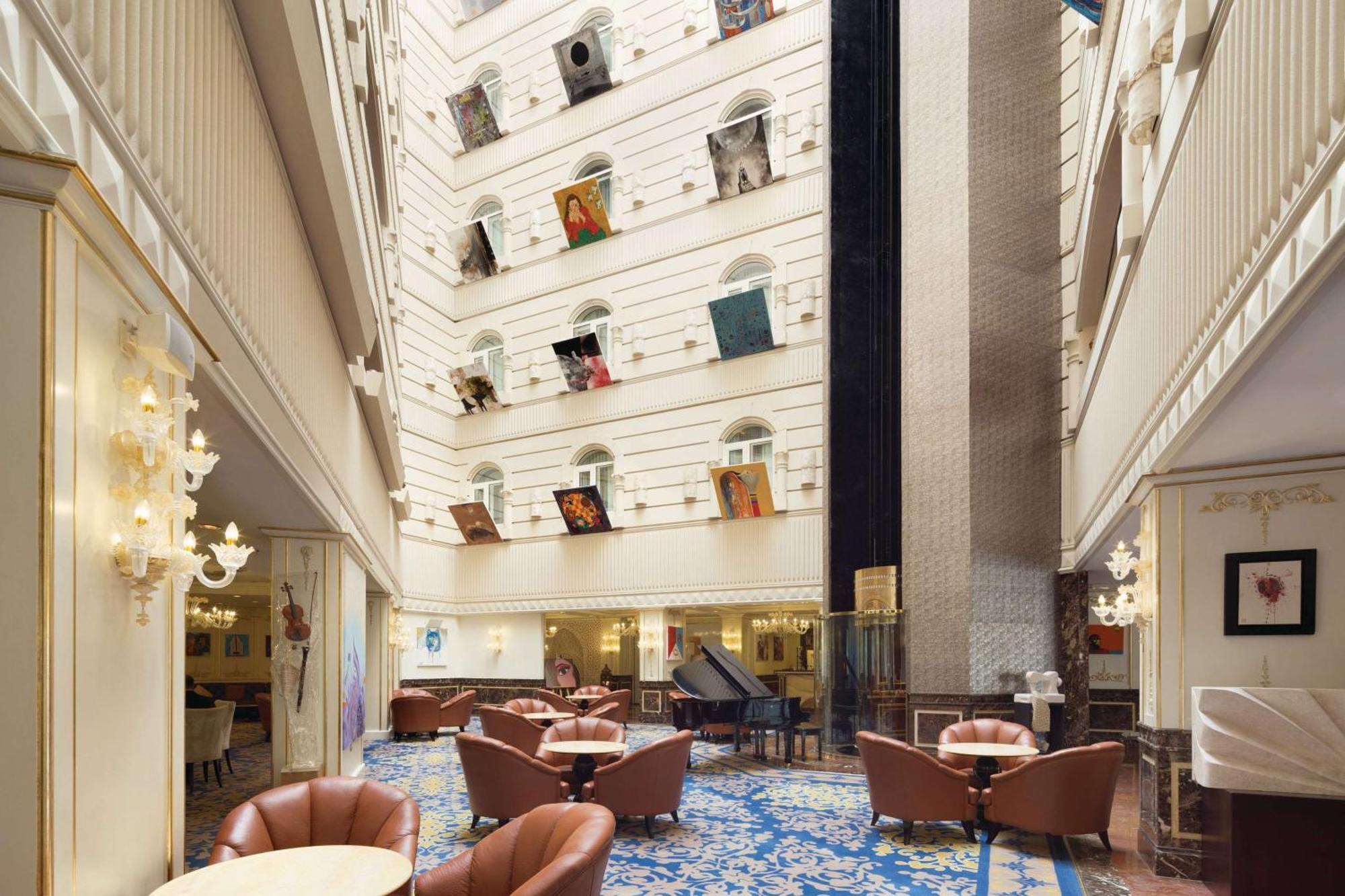 Grand Regency Doha, Trademark Collection By Wyndham Екстериор снимка The photo depicts the interior of a spacious, upscale hotel lobby. The design features high ceilings and multiple levels, with large windows that create a bright and airy atmosphere. Elegant light fixtures adorn the walls, and the floor is covered wi